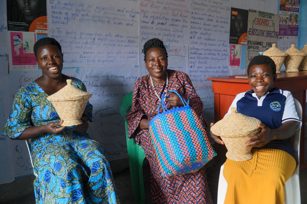 Juliet Mbambu (centre) and two members of the Bwera United Women with Disabilities Association (BUWDA) in Uganda display some of the artisanal baskets that the group crafts. Led by Mbambu, BUWDA actively fosters peace and dialogue in the community while also empowering women with disabilities. Photo: UN Women/Solomon Tumwesigye.