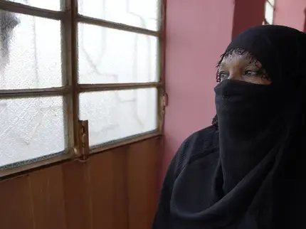 On 10 December 2024 in Sudan, Omnia [NAME CHANGED] peers through the window during a visit to a women’s organization. Displaced from her home due to fighting and threats, she lives with the trauma of being kidnapped, threatened, beaten and raped by armed men. To support her healing, Omnia is receiving mental health and psychosocial support from a women’s organization. Photo: UNICEF/UNI754435/Tess Ingram