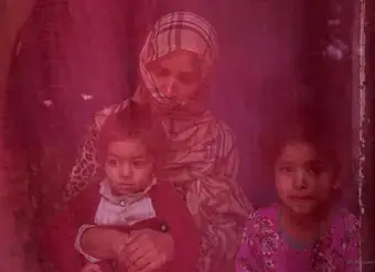 Now unemployed, a woman sits at home with her two daughters. Photo: UN Women/Sayed Habib Bidell.