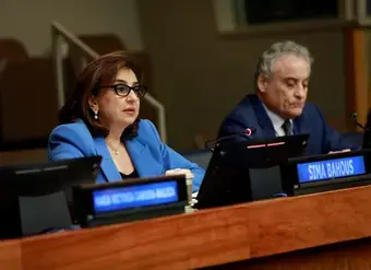 A woman in a blue blazer speaks at a microphone at UN headquarters