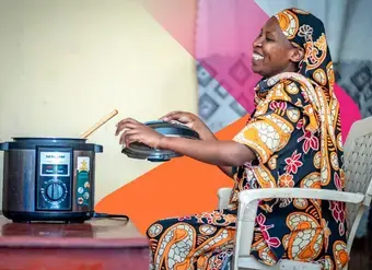 A UN Women programme beneficiary uses an improved cookstove, which has helped her significantly reduce the hours she spends preparing food. Photo: UN Women Tanzania.