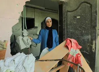 In February 2025, a woman in Gaza stands in the doorway of an apartment destroyed by explosion. Photo: UN Women/Suad Al Nawajha
