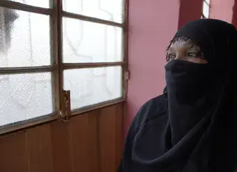 On 10 December 2024 in Sudan, Omnia [NAME CHANGED] peers through the window during a visit to a women’s organization. Displaced from her home due to fighting and threats, she lives with the trauma of being kidnapped, threatened, beaten and raped by armed men. To support her healing, Omnia is receiving mental health and psychosocial support from a women’s organization. Photo: UNICEF/UNI754435/Tess Ingram
