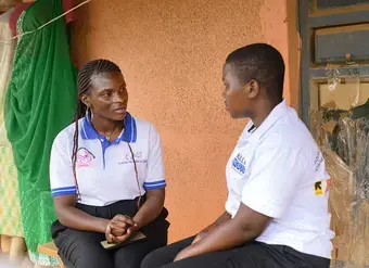 A young Ugandan woman sits with another local woman to talk