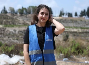 A young woman poses for a portrait while wearing a UN Women vest