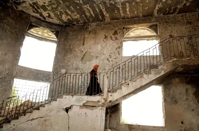 A woman walks up the stairs of a damaged building