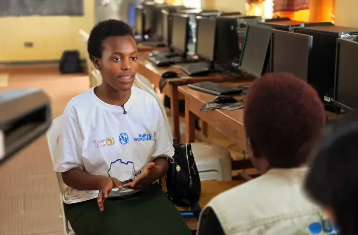 Victoria Komekyeya sits in a computer lab and speaks with UN Women staff