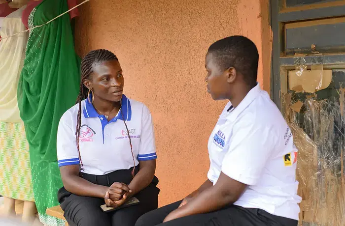 Une jeune Ougandaise est assise aux côtés d'une autre femme de la région pour discuter