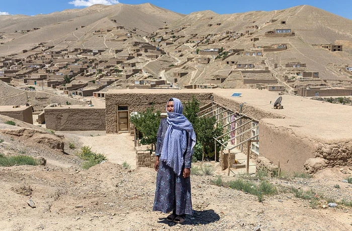 An Afghan woman stands outside her village