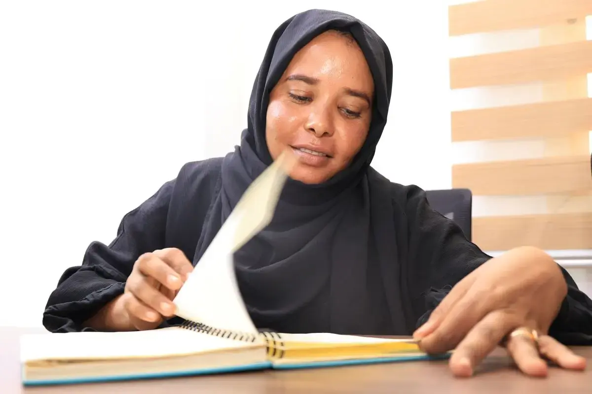 Areej Hussein, a young Sudanese woman, flips through a notebook