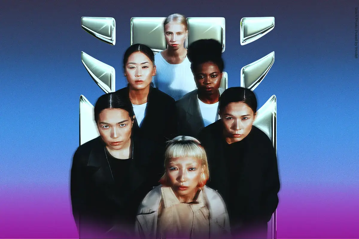 Six women standing closely together against a blue-to-purple gradient background, facing the camera with serious expressions. They are positioned in two rows, with a metallic UN Women logo displayed behind them. The women have diverse appearances and wear dark and neutral-toned clothing, creating a strong, unified group portrait.