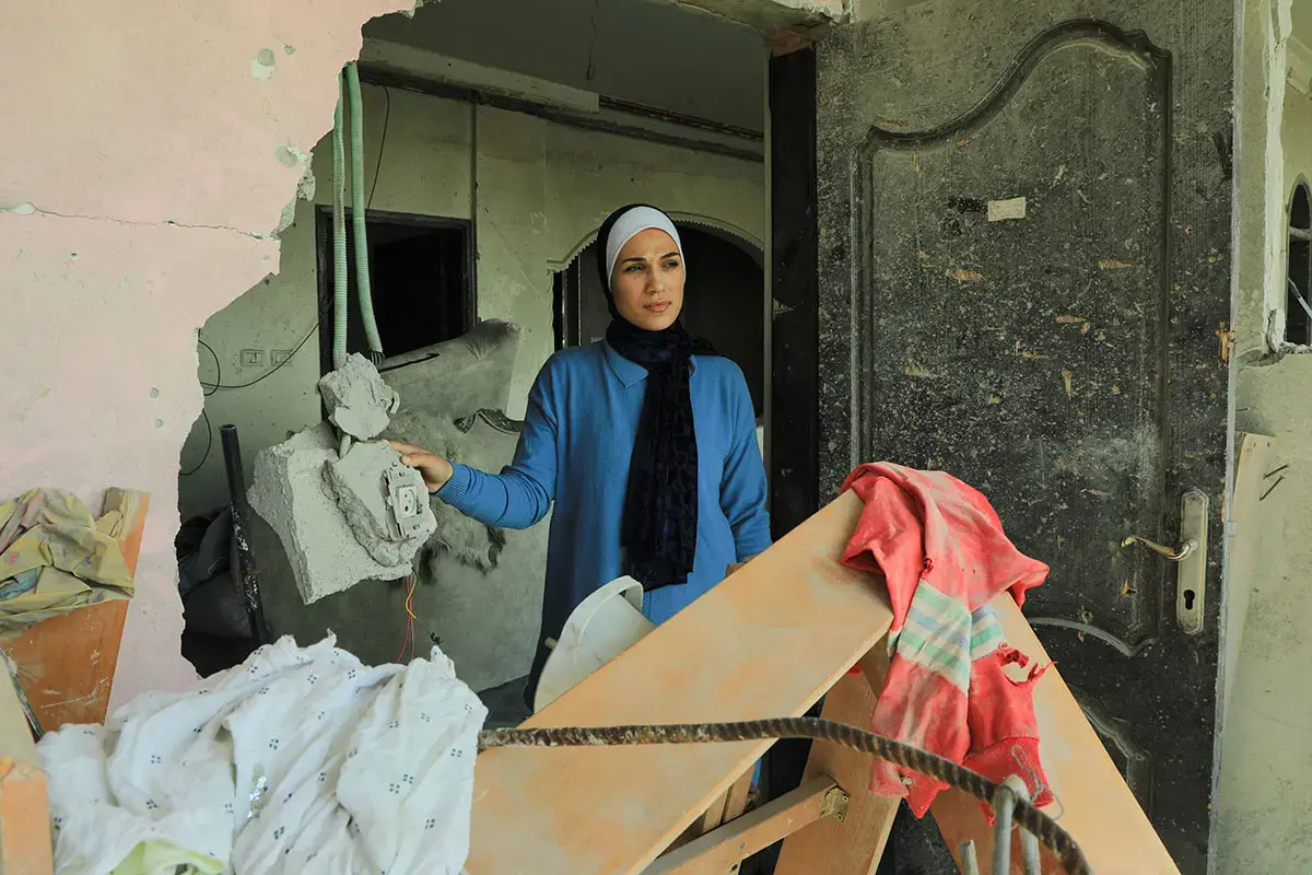 In February 2025, a woman in Gaza stands in the doorway of an apartment destroyed by explosion. Photo: UN Women/Suad Al Nawajha