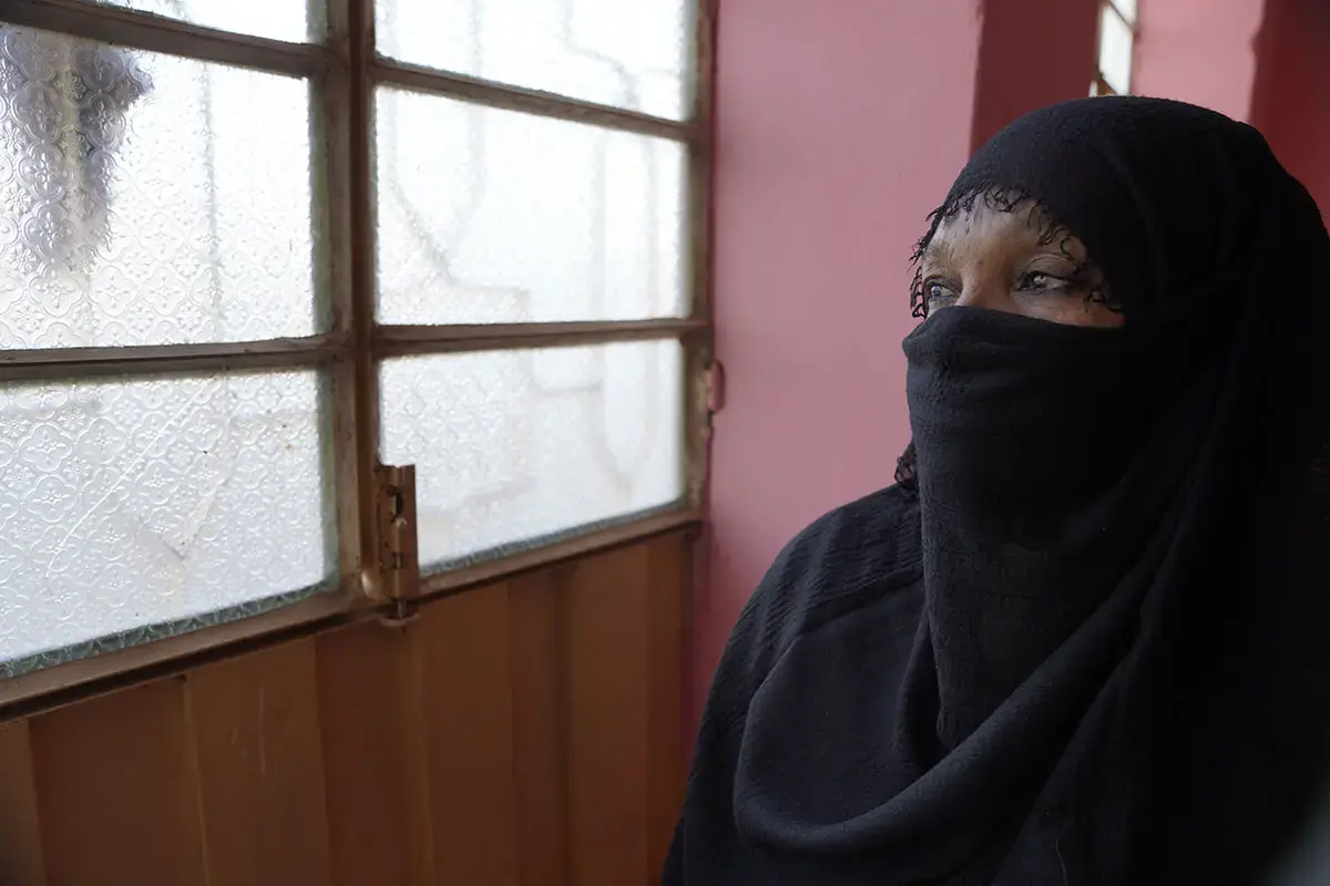 On 10 December 2024 in Sudan, Omnia [NAME CHANGED] peers through the window during a visit to a women’s organization. Displaced from her home due to fighting and threats, she lives with the trauma of being kidnapped, threatened, beaten and raped by armed men. To support her healing, Omnia is receiving mental health and psychosocial support from a women’s organization. Photo: UNICEF/UNI754435/Tess Ingram