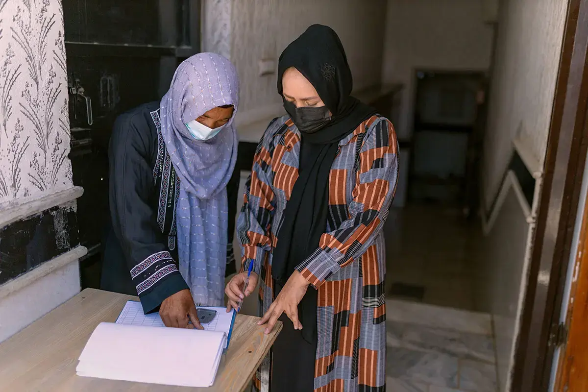 Two women fill in paperwork together at an organization.