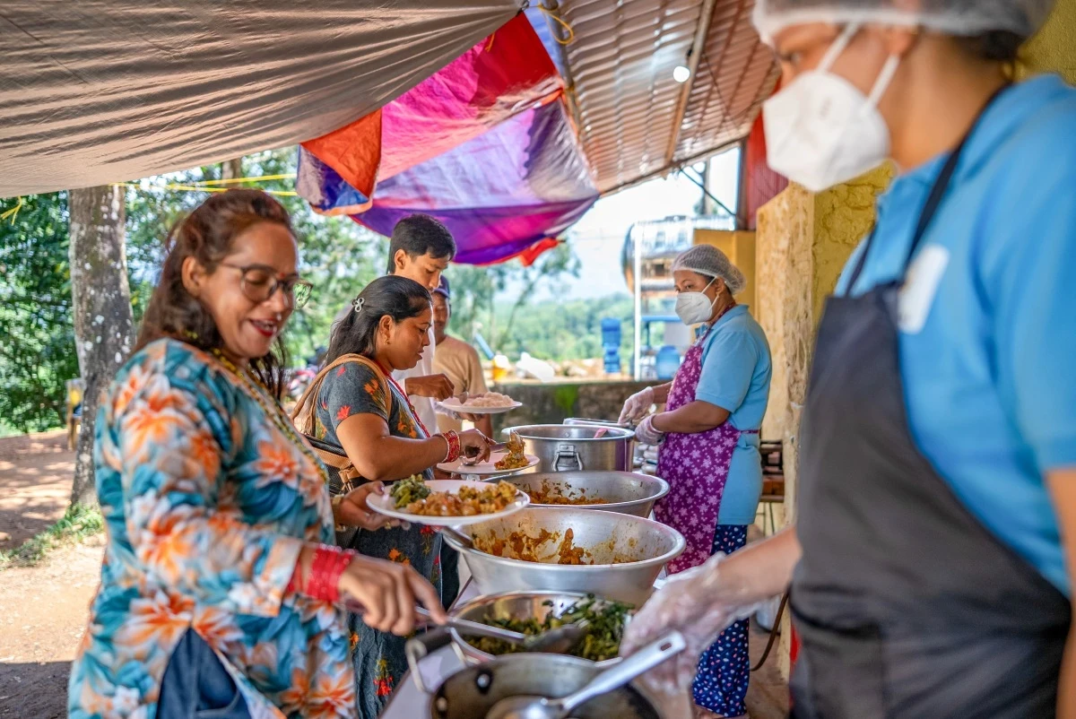 Two chefs serve food to local women standing in line