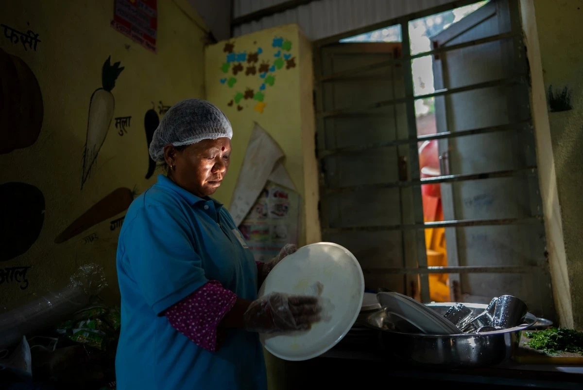 A woman washes a large serving platter while the sun shines on her face