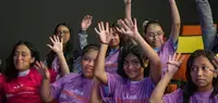Niñas elevando sus manos celebrando en evento con mujeres deportistas