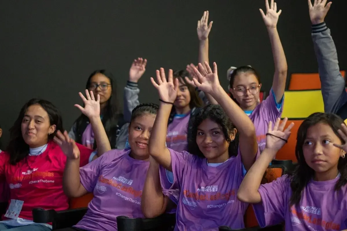 Niñas elevando sus manos celebrando en evento con mujeres deportistas