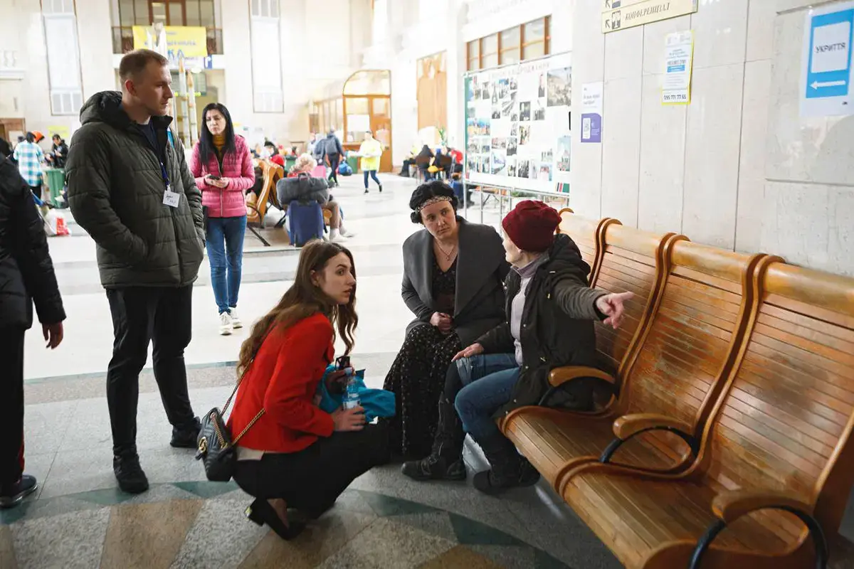 Three people gather around a displaced woman