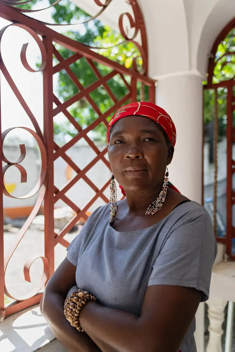 A portrait of a woman wearing a red headscarf and beaded earrings.