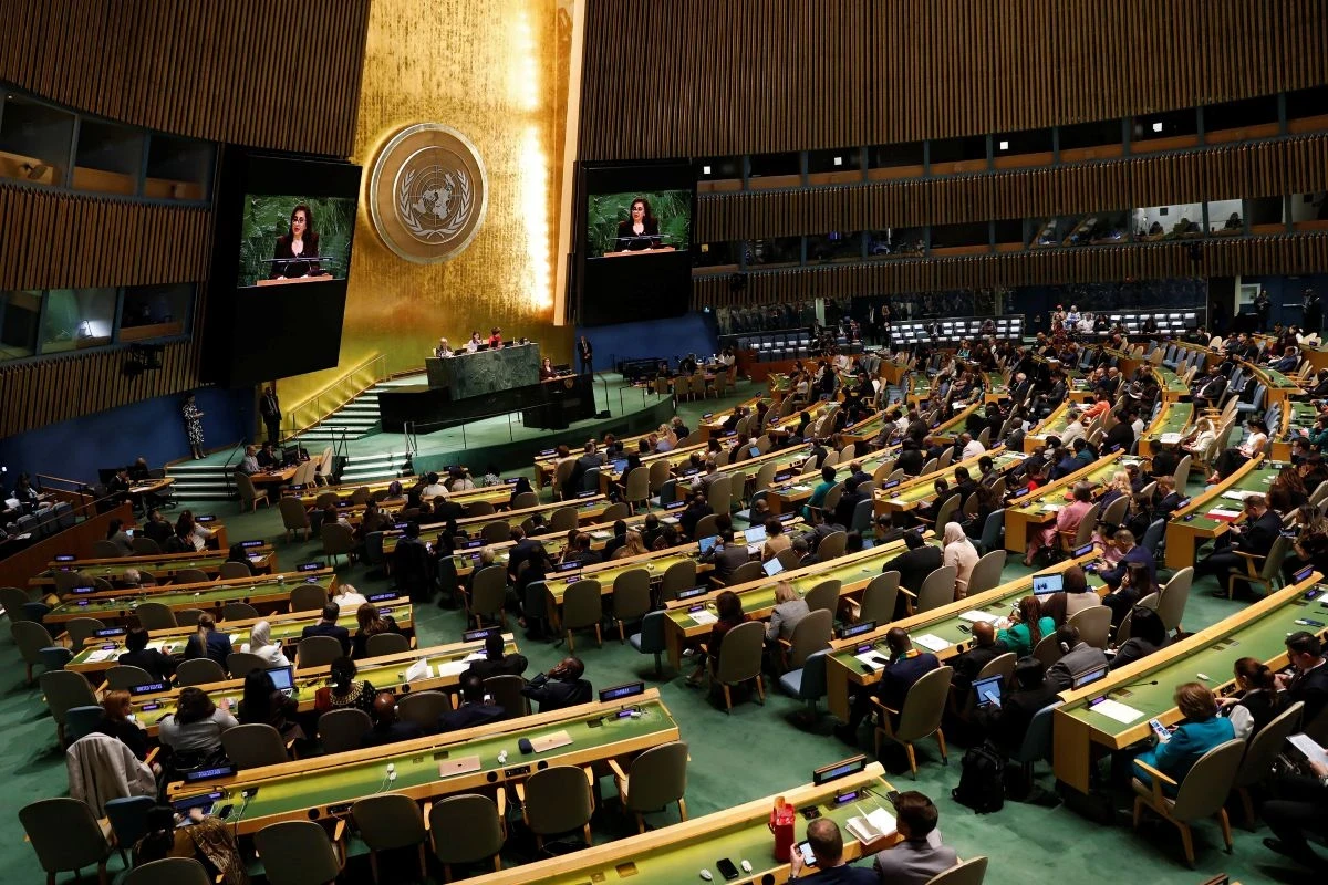 Sima Bahous speaks at a podium in front of a large auditorium