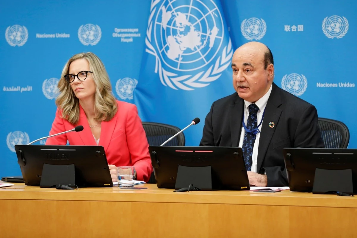 Sarah Hendricks and Shantanu Mukherjee speak to reporters in front of the United Nations banner